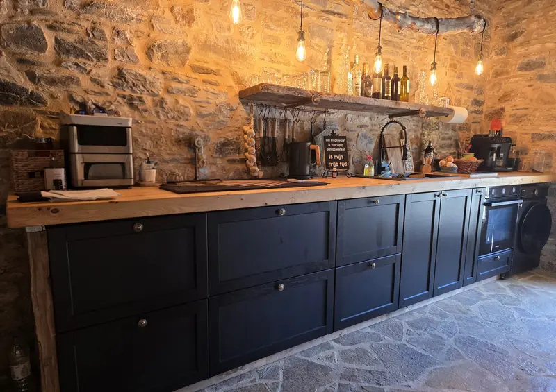 Long kitchen with black cabinets, a wooden worktop and bulbs on a branch