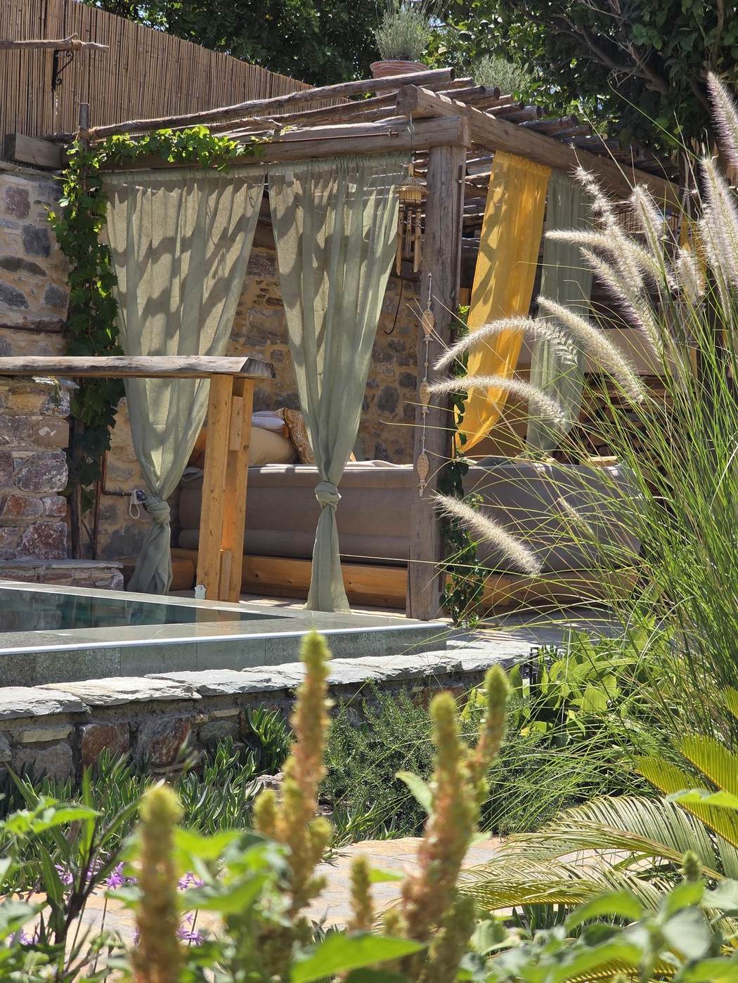 Pagoda with a daybed and linen curtains beside the pool