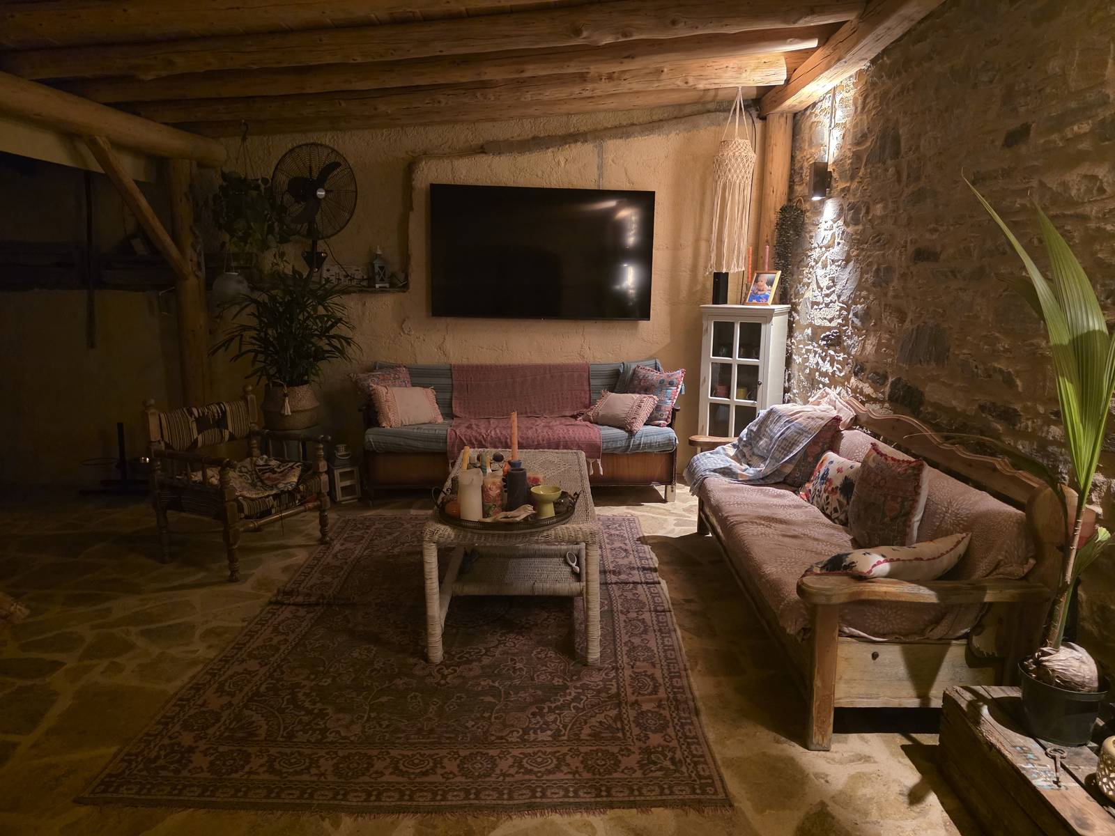 The living room in the evening, warm light under the wooden beams